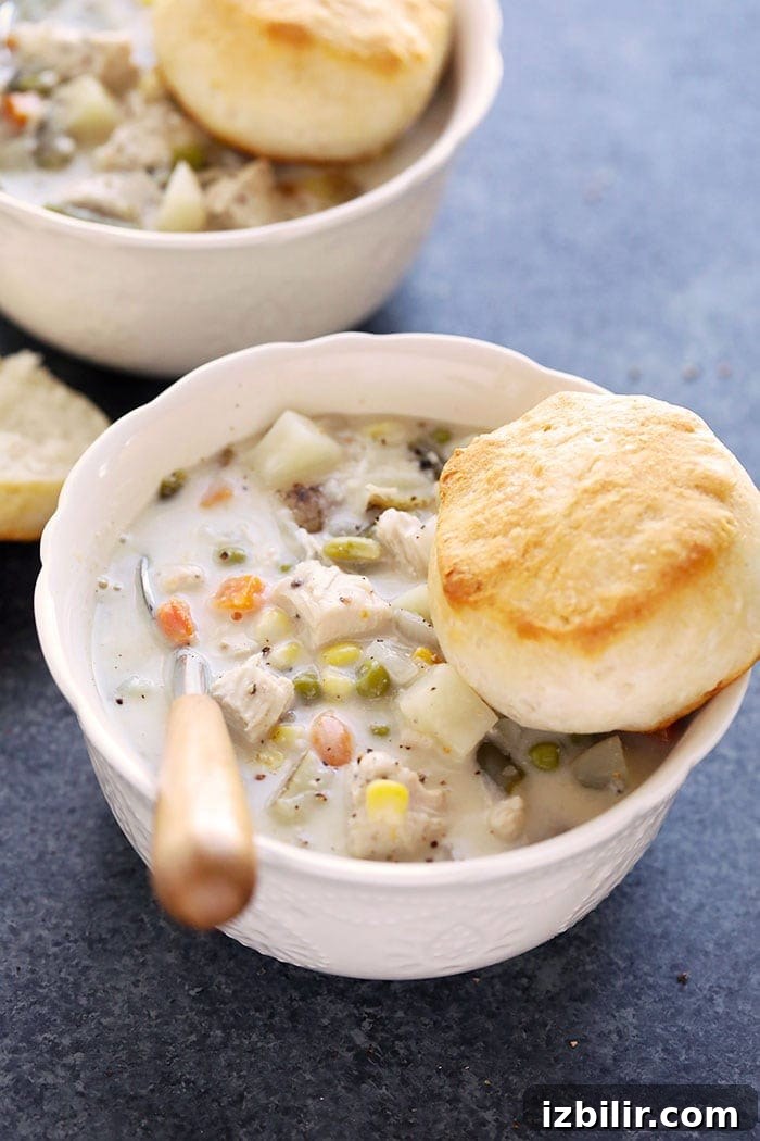 Slow Cooker Chicken Pot Pie Soup with Biscuit Slow cooker chicken pot pie soup in a bowl with a biscuit.