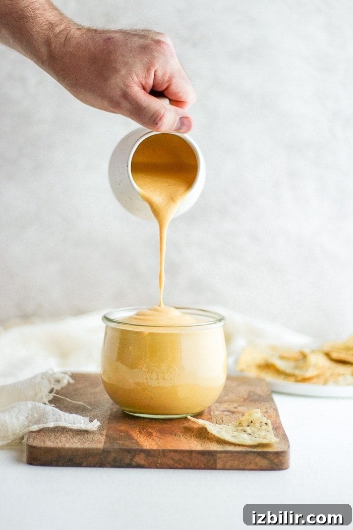 Creamy Vegan Cheese Sauce Recipe 5 pouring vegan cheese sauce into jar.