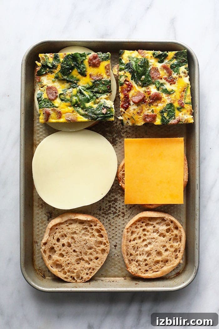 assembling make ahead freezer breakfast sandwiches on a sheet pan.
