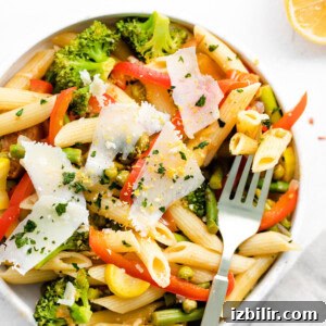 A bowl of pasta primavera with vegetables and Parmesan cheese.