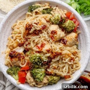 Bowl of ramen noodles with pieces of chicken, broccoli, red bell peppers