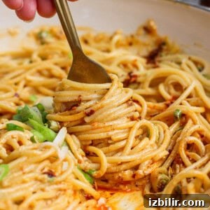 Fork twirling spaghetti noodles coated in creamy orange sauce