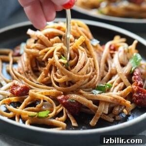 Sun dried tomato pasta being twirled on fork