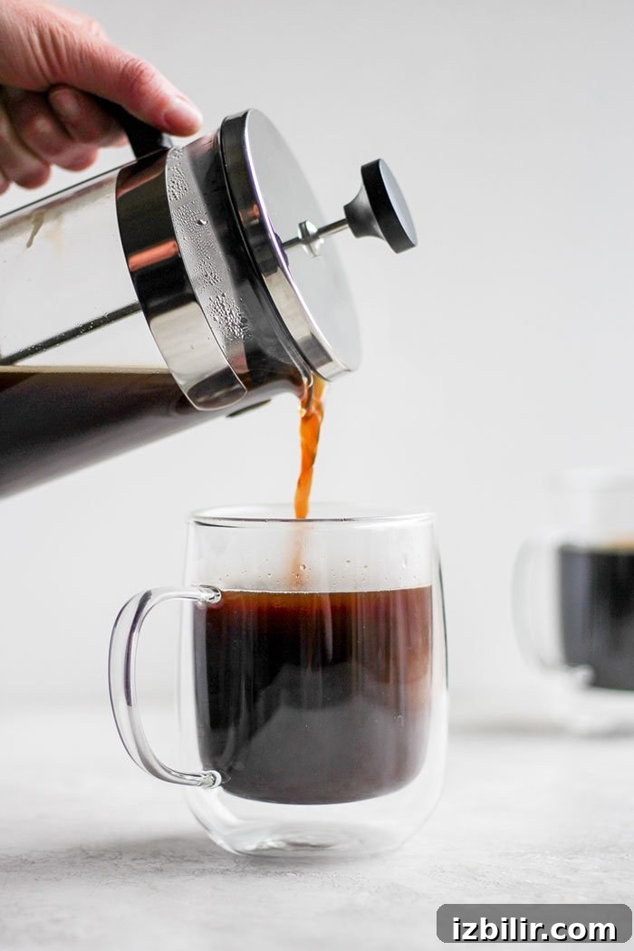 Start the day off right with the perfect cup of French press coffee! Pouring coffee from a french press into a mug.