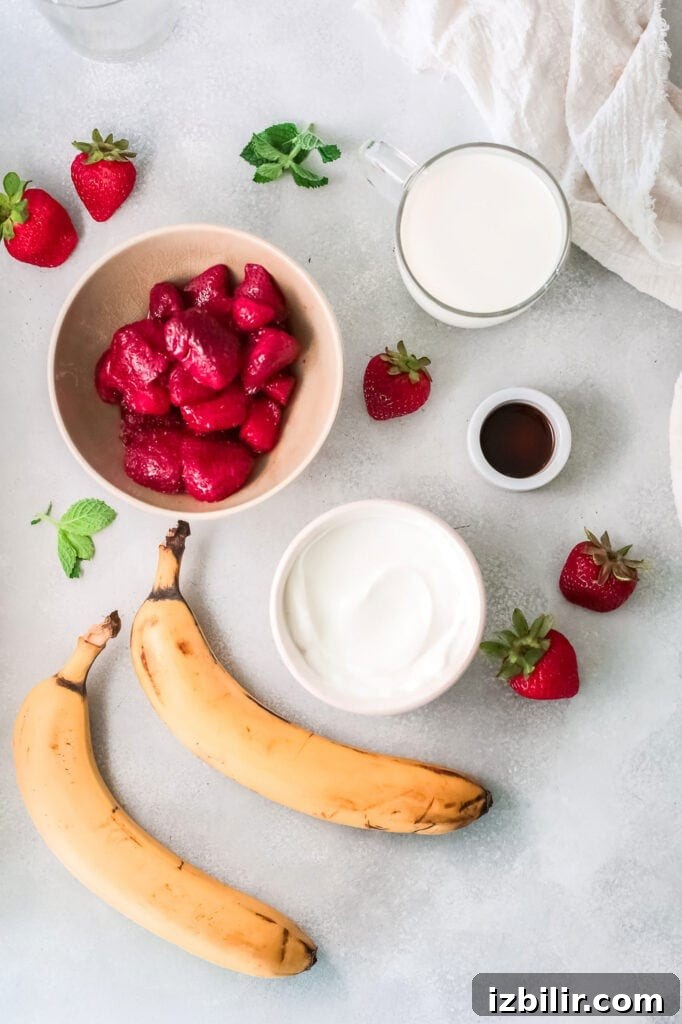 Smoothie ingredients: frozen strawberries, frozen banana, Greek yogurt, vanilla, and almond milk. smoothie ingredients on counter