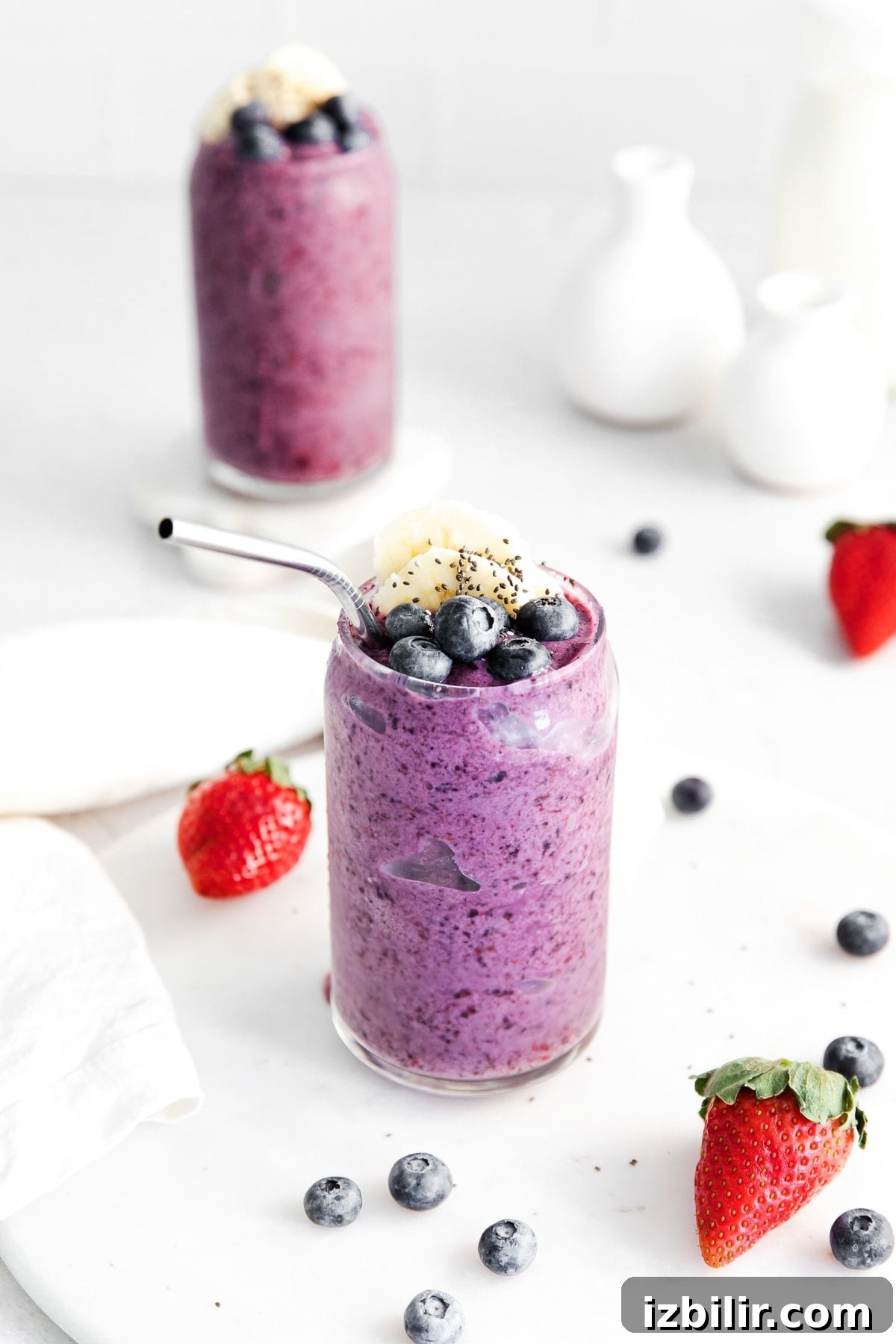 Triple Berry Smoothie with Fresh Blueberries triple berry smoothie in a glass topped with fresh blueberries.