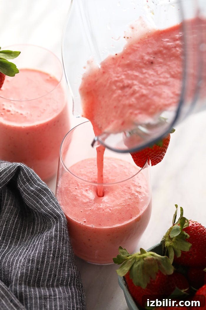 Strawberry smoothie being poured into a glass.