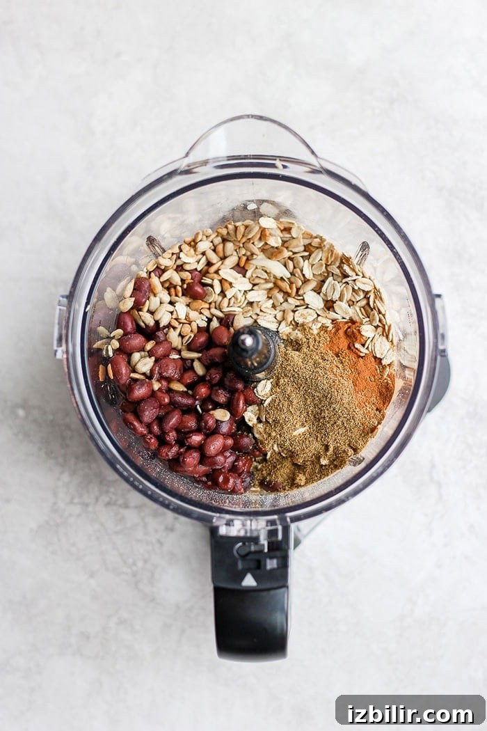 Ingredients for black bean burgers in a food processor Black beans, seeds, oats, and spices in a food processor