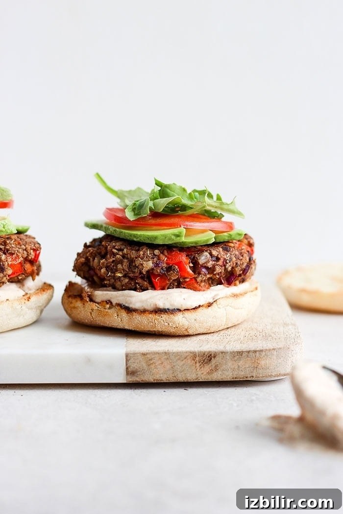 Black bean quinoa burger with avocado and tomato quinoa burgers on an english muffin with sauce, avocado, tomato, and arugula