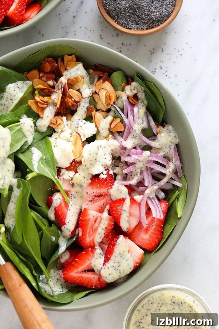 Strawberry spinach salad in a bowl topped with feta and candied almonds.