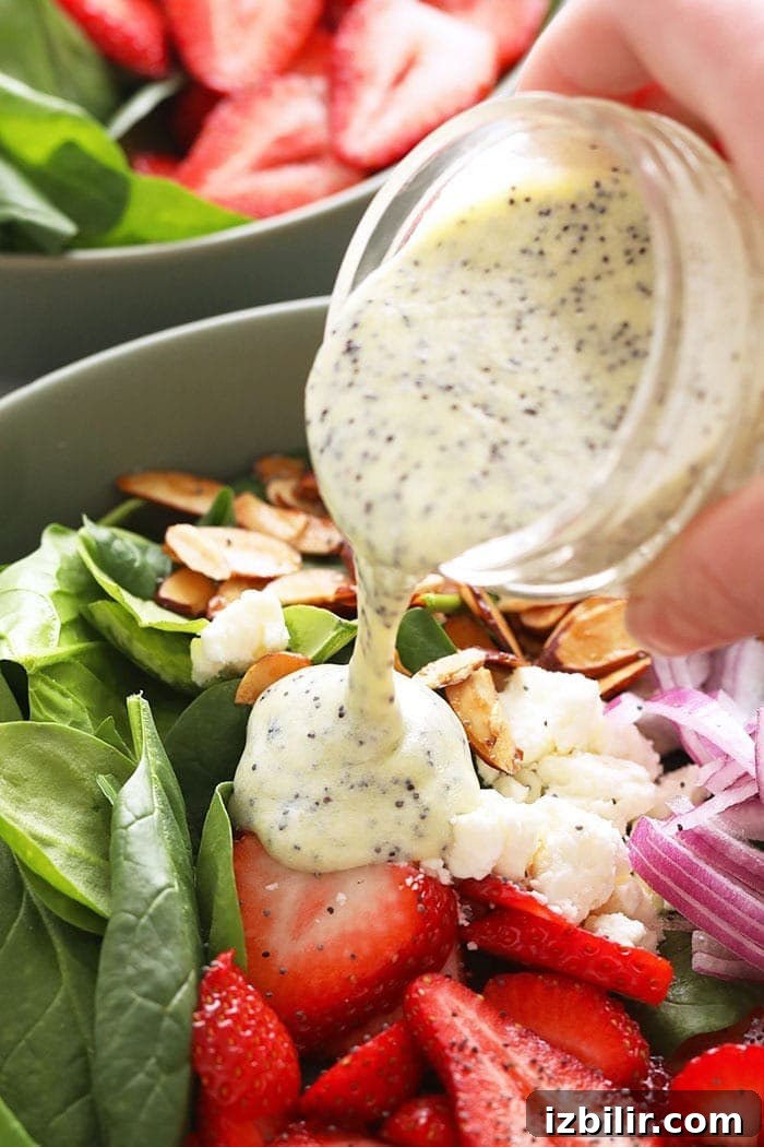 Homemade Creamy Poppy Seed Salad Dressing 3 Dressing being poured over salad ingredients.