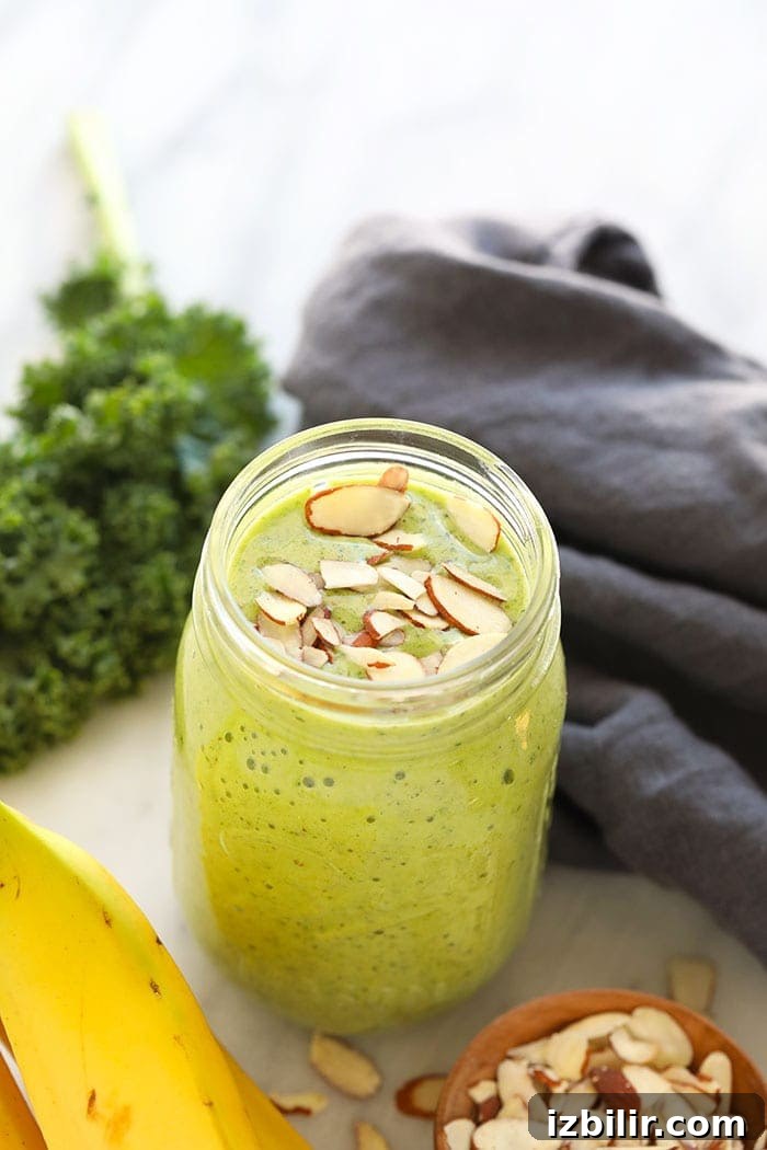 Get your daily greens here! This is the most delicious kale smoothie you'll ever make! It's packed with nutrient dense kale, frozen bananas and the perfect flavor punch of orange juice and fresh ginger. Whip up this green smoothie in 5 minutes and you're off and running with a healthy breakfast or snack on the go. kale smoothie in a mason jar.