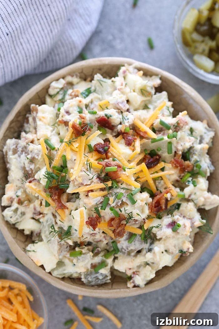 This baked potato salad is loaded with cheese, bacon, chives, hard boiled egg, and a delicious dill pickle sauce that's actually healthy! A bowl of loaded baked potato salad