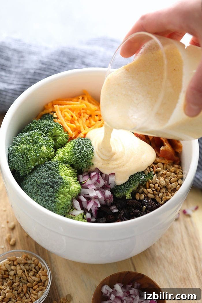 Pouring sauce for healthy broccoli salad onto ingredients.