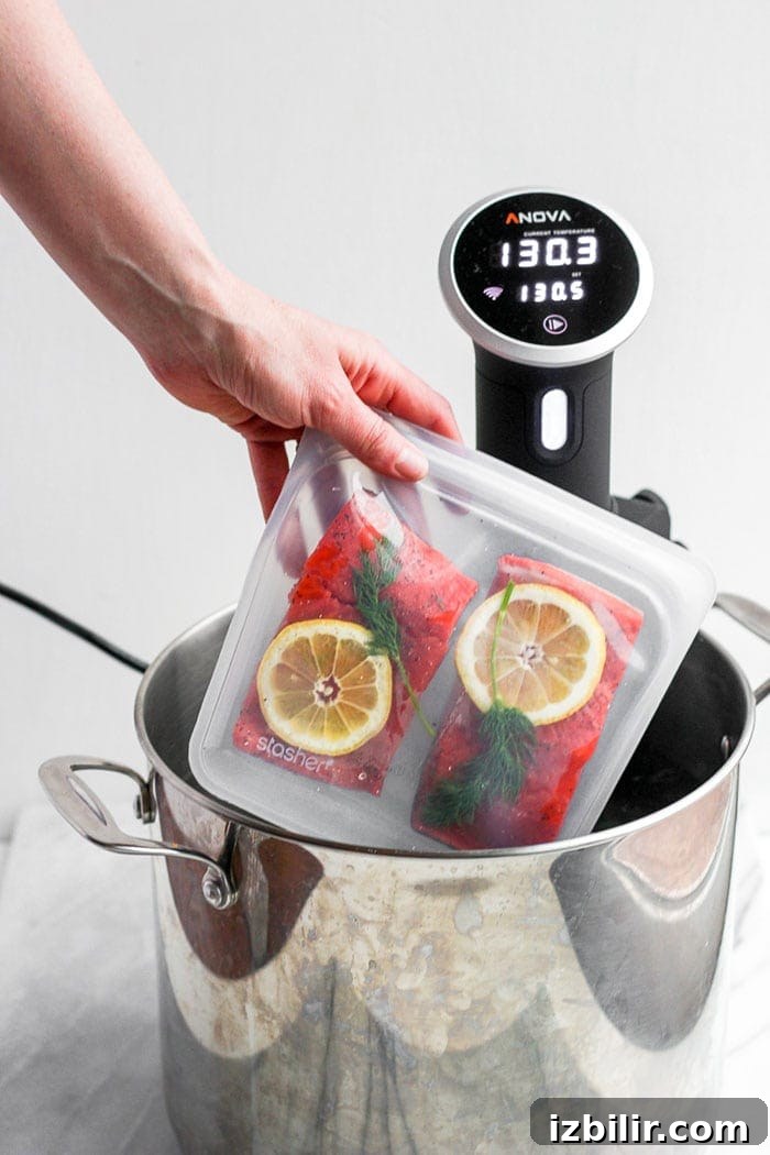 Placing salmon into the sous vide bath. Sous vide salmon going into the sous vide.