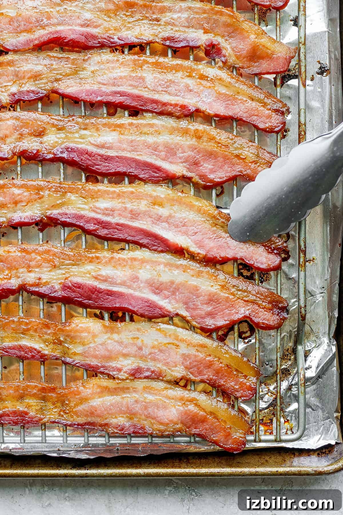 bacon on a baking sheet with a fork.
