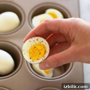 A person using an oven to hard boil eggs in a muffin tin.