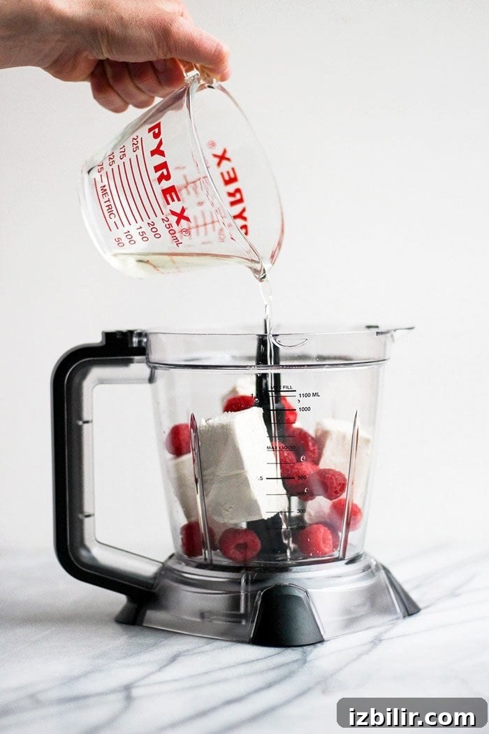 Keto Raspberry Cheesecake Fat Bombs 4 pouring coconut oil into food processor