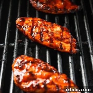 three grilled chicken breasts on a grill.