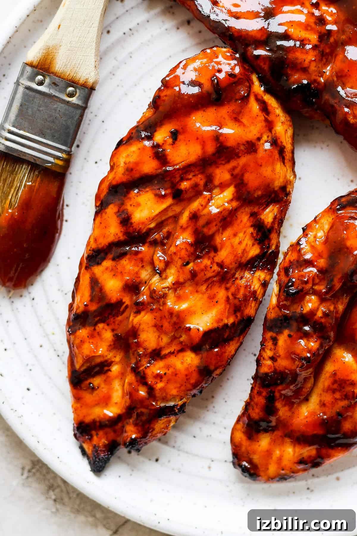 bbq grilled chicken on a white plate with a brush.