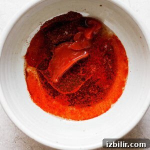 a white bowl with a red sauce in it.