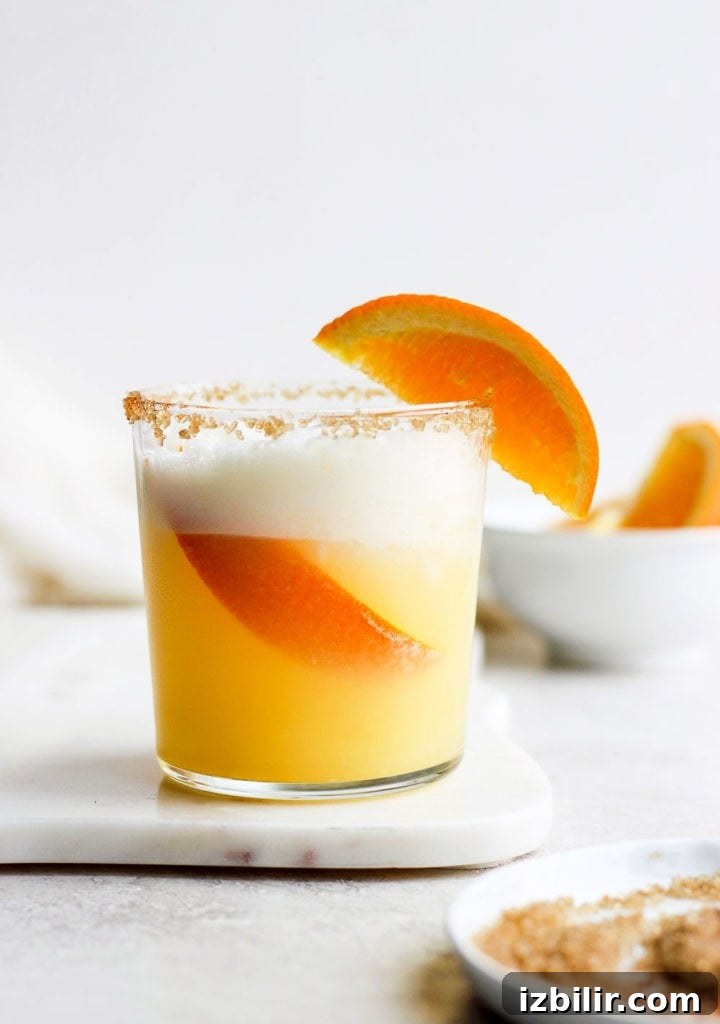 15+ Vodka Cocktail Recipes You Need to Try Tonight 10 An orange cocktail garnished with a slice of orange.