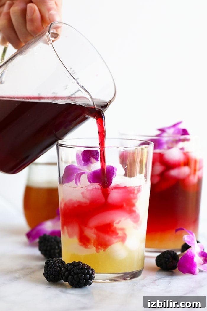 Hibiscus Arnold Palmer drink in a glass topped with edible flowers hibiscus arnold palmer drink in a glass topped with edible flowers