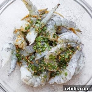 Grilled prawns in a glass bowl with herbs, marinade.