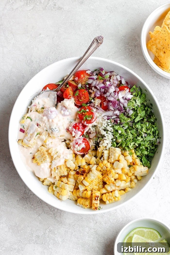 Take dinner up a notch and add this Mexican Street Corn Salad to the menu! This delicious healthy side dish is made with grilled corn, fresh veggies, and the most delicious cotija yogurt sauce. Drop everything you're doing and make this Mexican Street Corn Salad today! Mexican Street Corn Salad in a bowl.