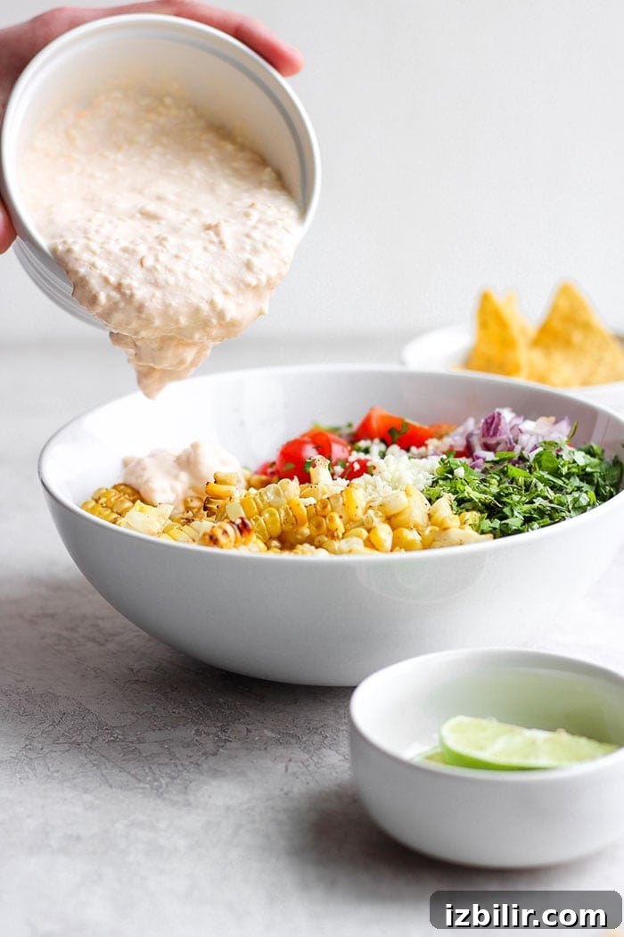 Pouring sauce onto the Mexican Street Corn Salad. Pouring sauce onto the Mexican Street Corn Salad.