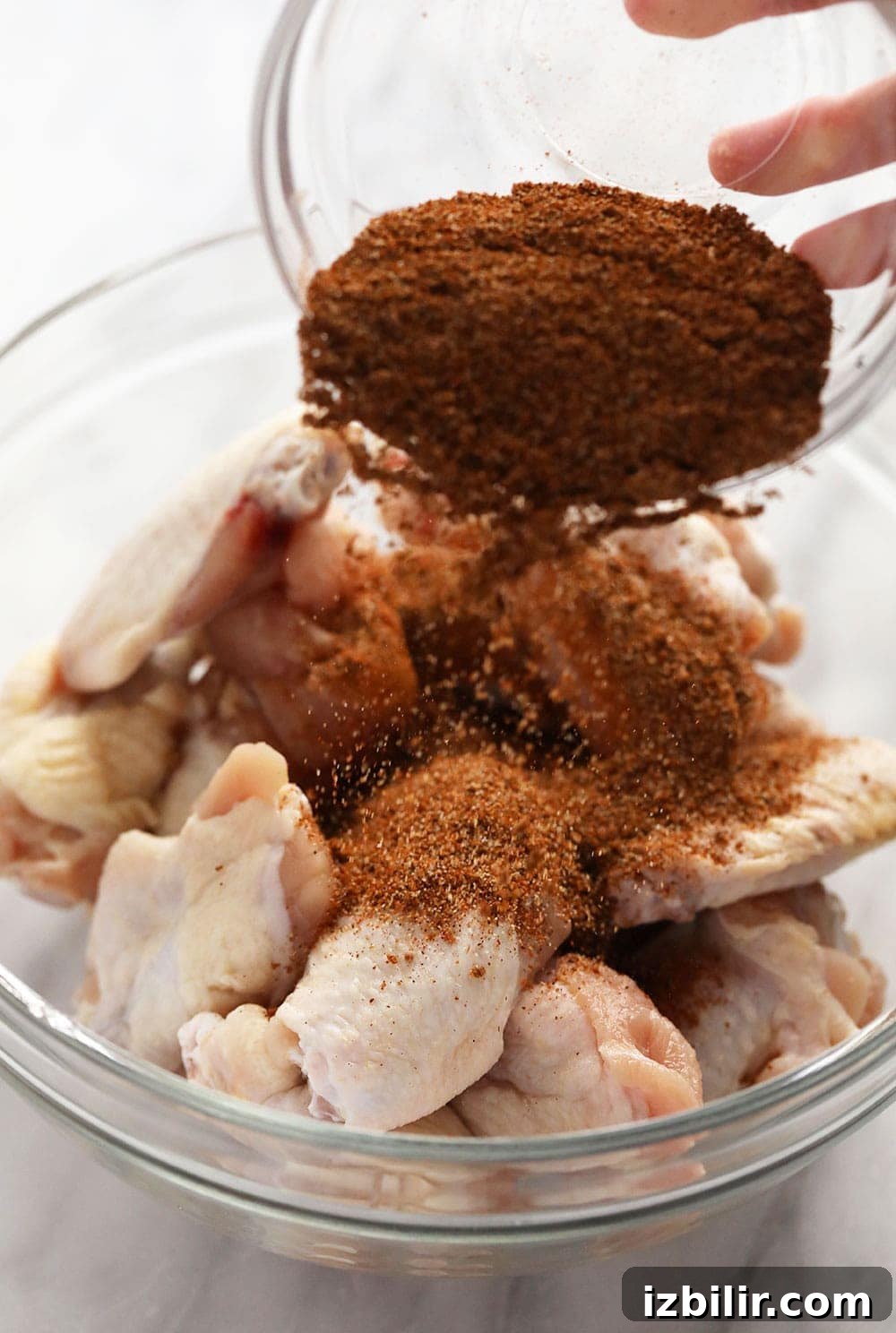 Coating wings in dry rub Pouring dry rub over chicken wings