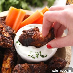Enjoying dry rub chicken wings A person enjoying dry rub wings by dipping them into a bowl of dip