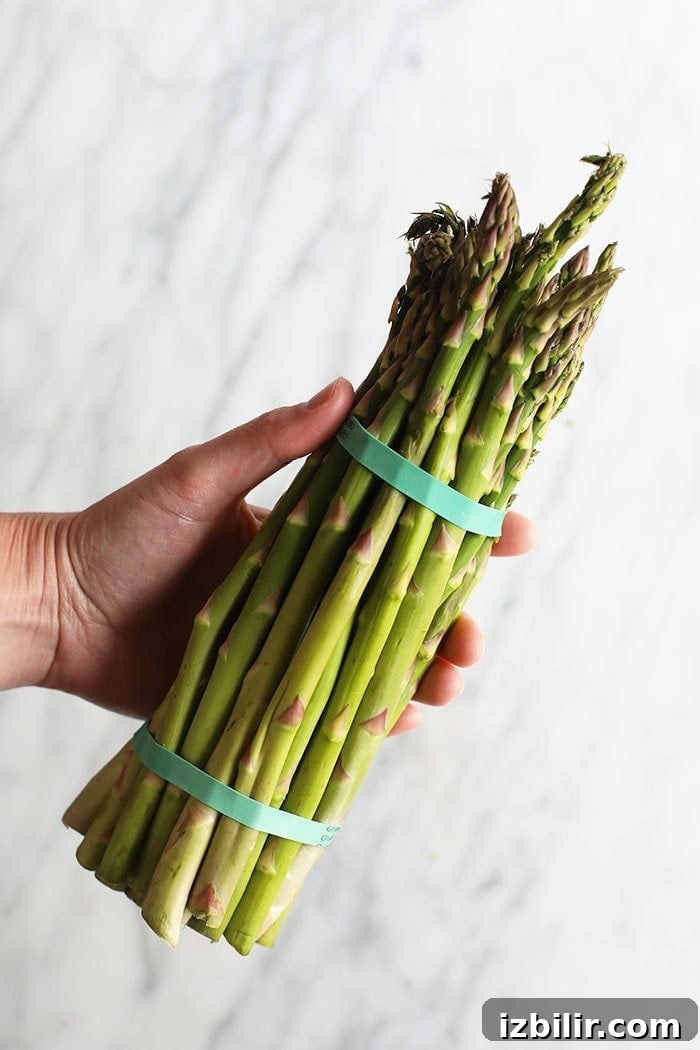 a bundle of fresh asparagus spears on a cutting board