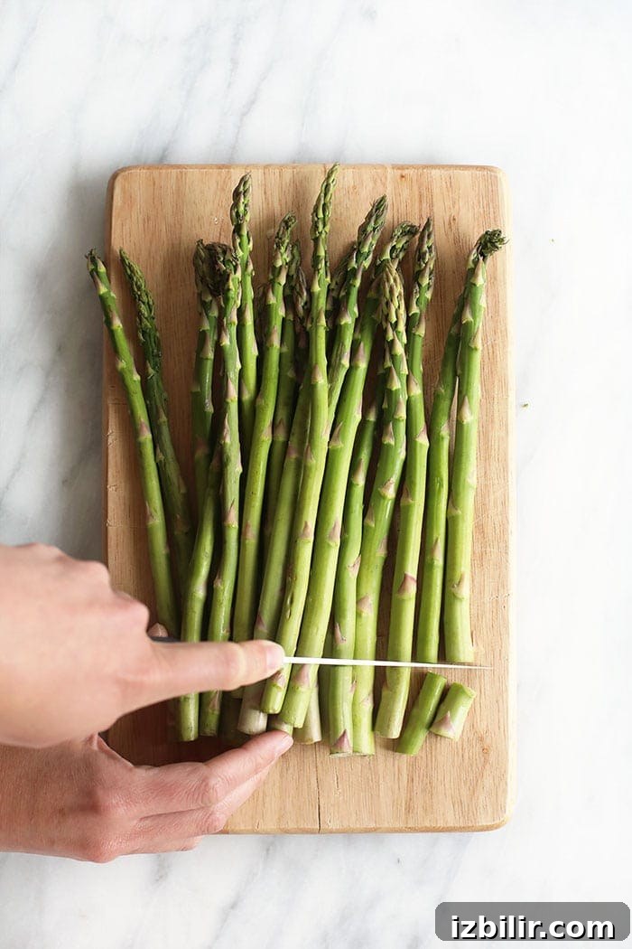 trimming the woody ends off asparagus spears with a knife