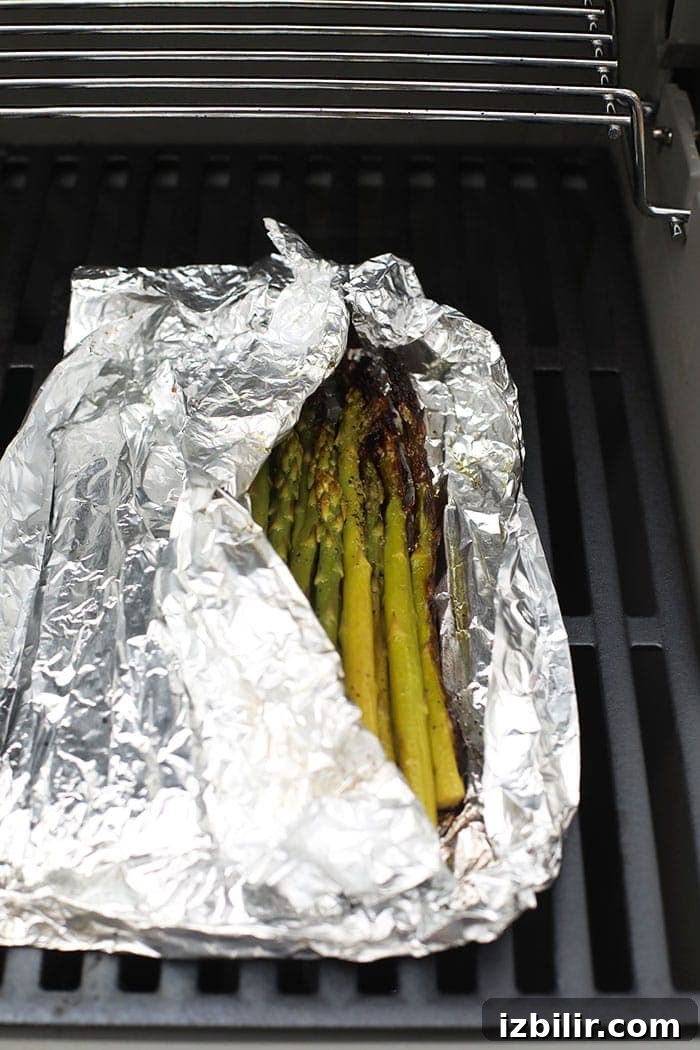 a foil packet of asparagus on a hot grill