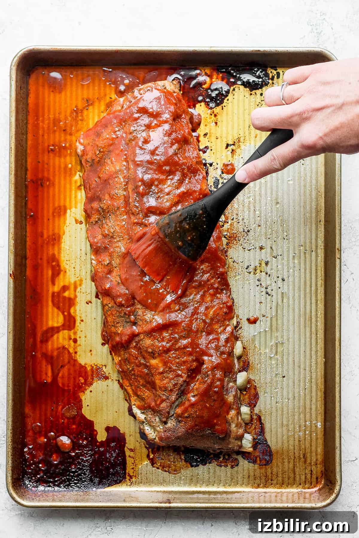 homemade BBQ sauce being used on a rack of ribs.