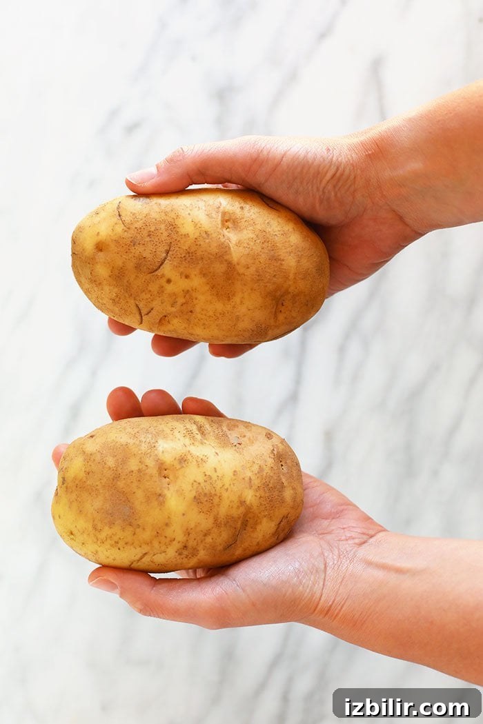 Crispy Foil-Wrapped Baked Potatoes 2 hands holding potatoes