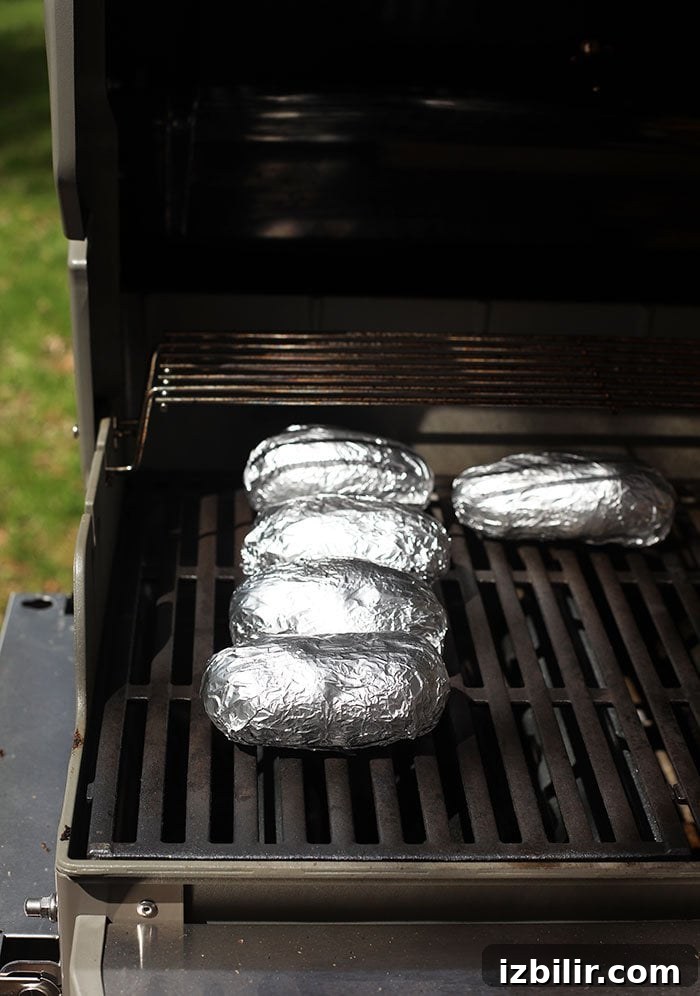Crispy Foil-Wrapped Baked Potatoes 5 baked potatoes in foil on grill grates