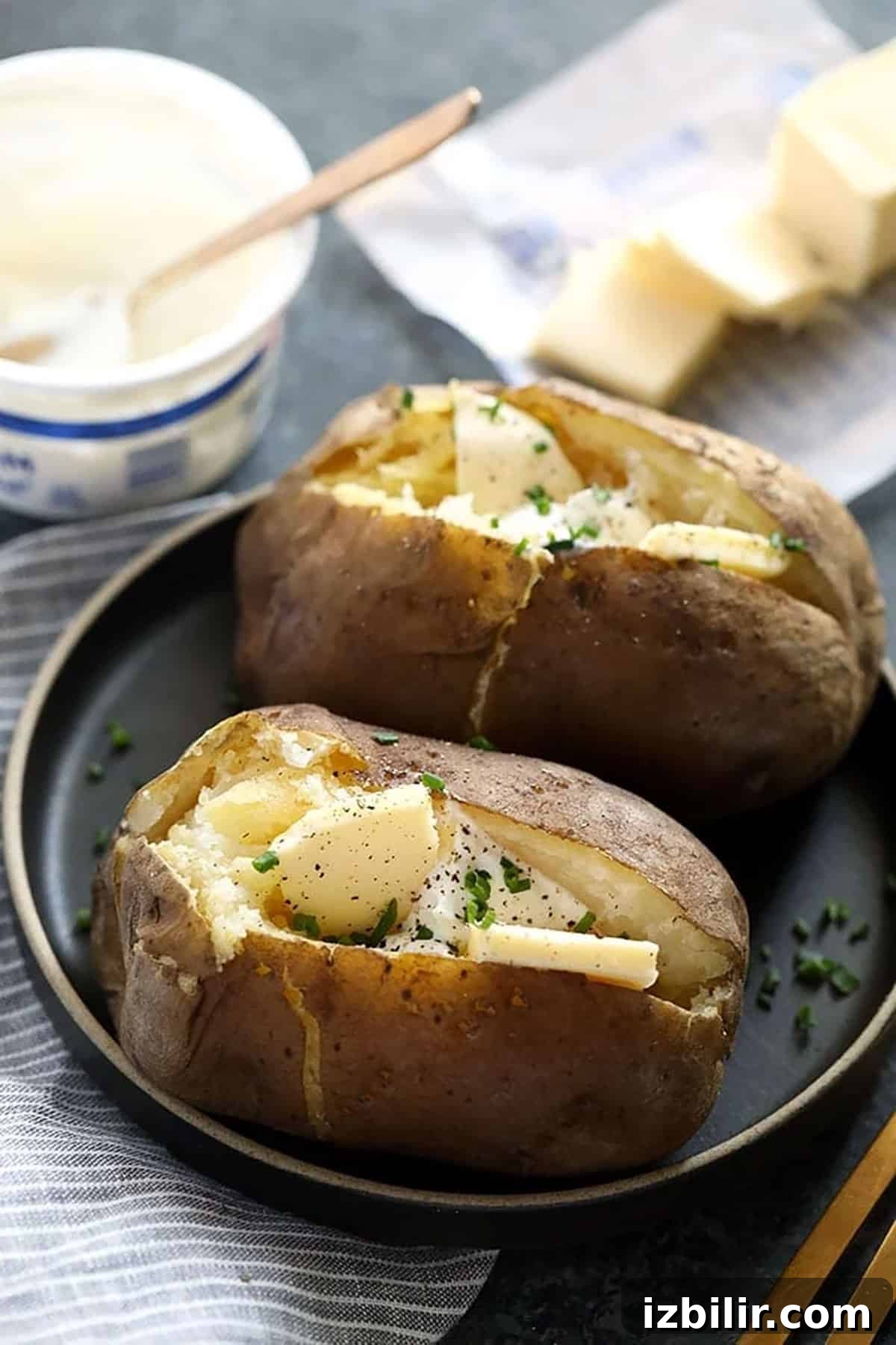 Two crock pot baked potatoes with cheese on a plate.