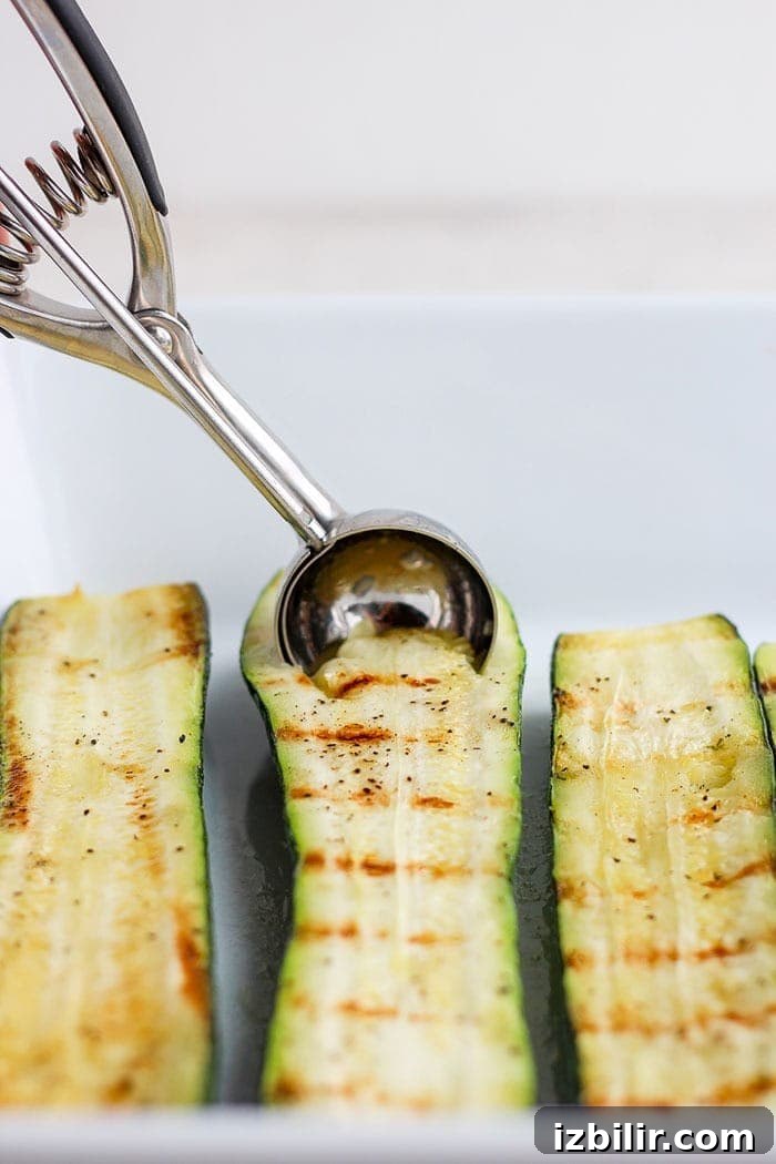 sliced zucchini being scooped with a melon baller