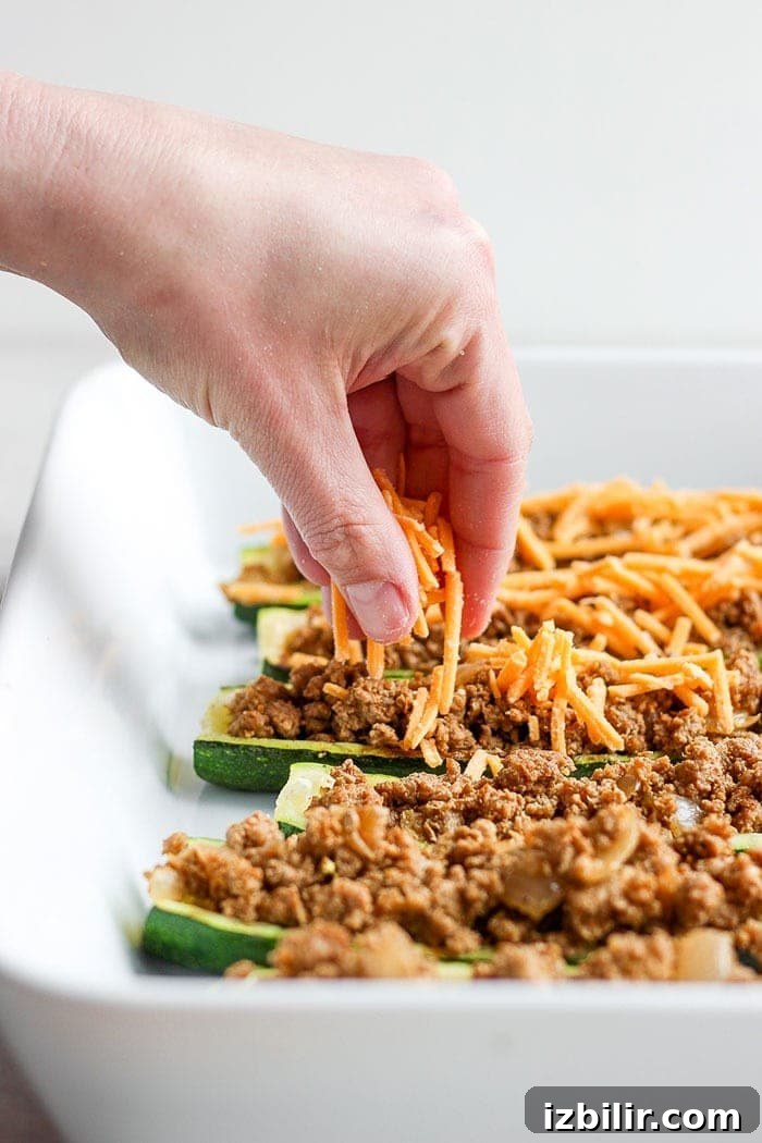 taco zucchini boats being sprinkled with cheese