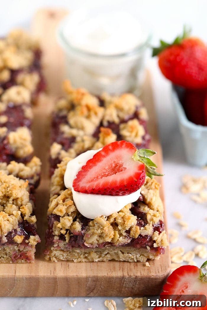 Strawberry Oatmeal Bars Recipe 2 strawberry oatmeal bars sliced on a cutting board and topped with a strawberry