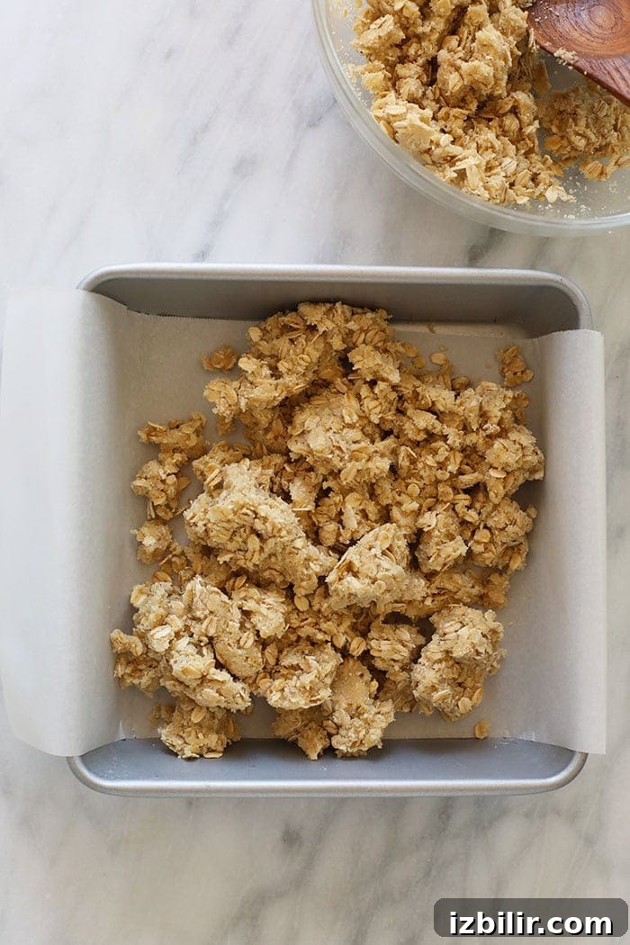 Strawberry Oatmeal Bars Recipe 4 crust and crumble topping in a baking dish with parchment paper