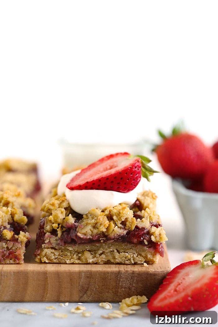 Strawberry Oatmeal Bars Recipe 8 strawberry oatmeal bar sliced and topped with whipped cream and a sliced fresh strawberry