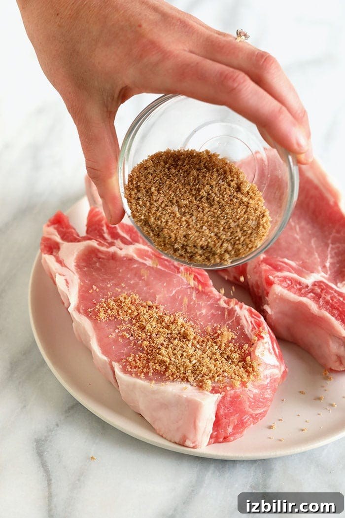 Spice rub going onto pork chops pouring spices on pork