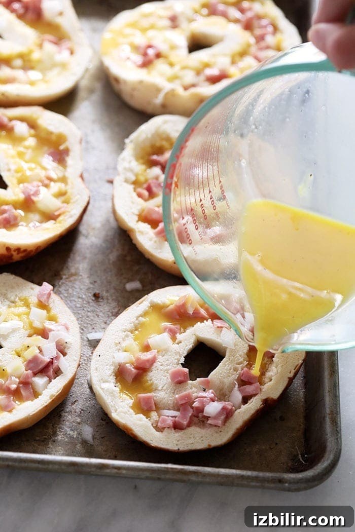 Filling bagels with egg Pouring egg into hallowed out bagels
