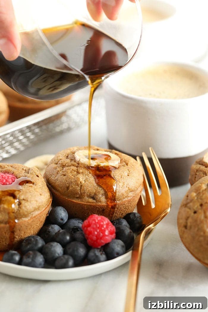 banana pancake muffins being drizzled with maple syrup