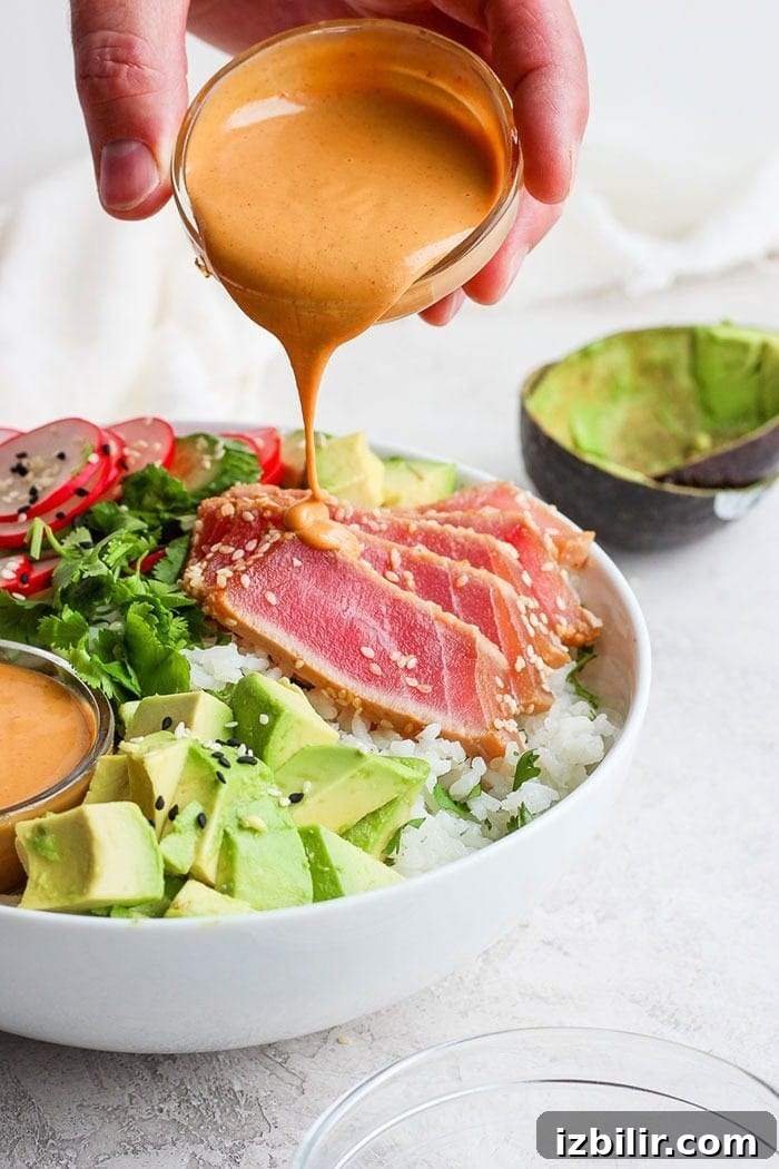 Drizzling almond dressing onto the poke bowl