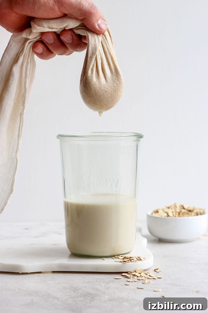 filtering out oat milk in a tea towel