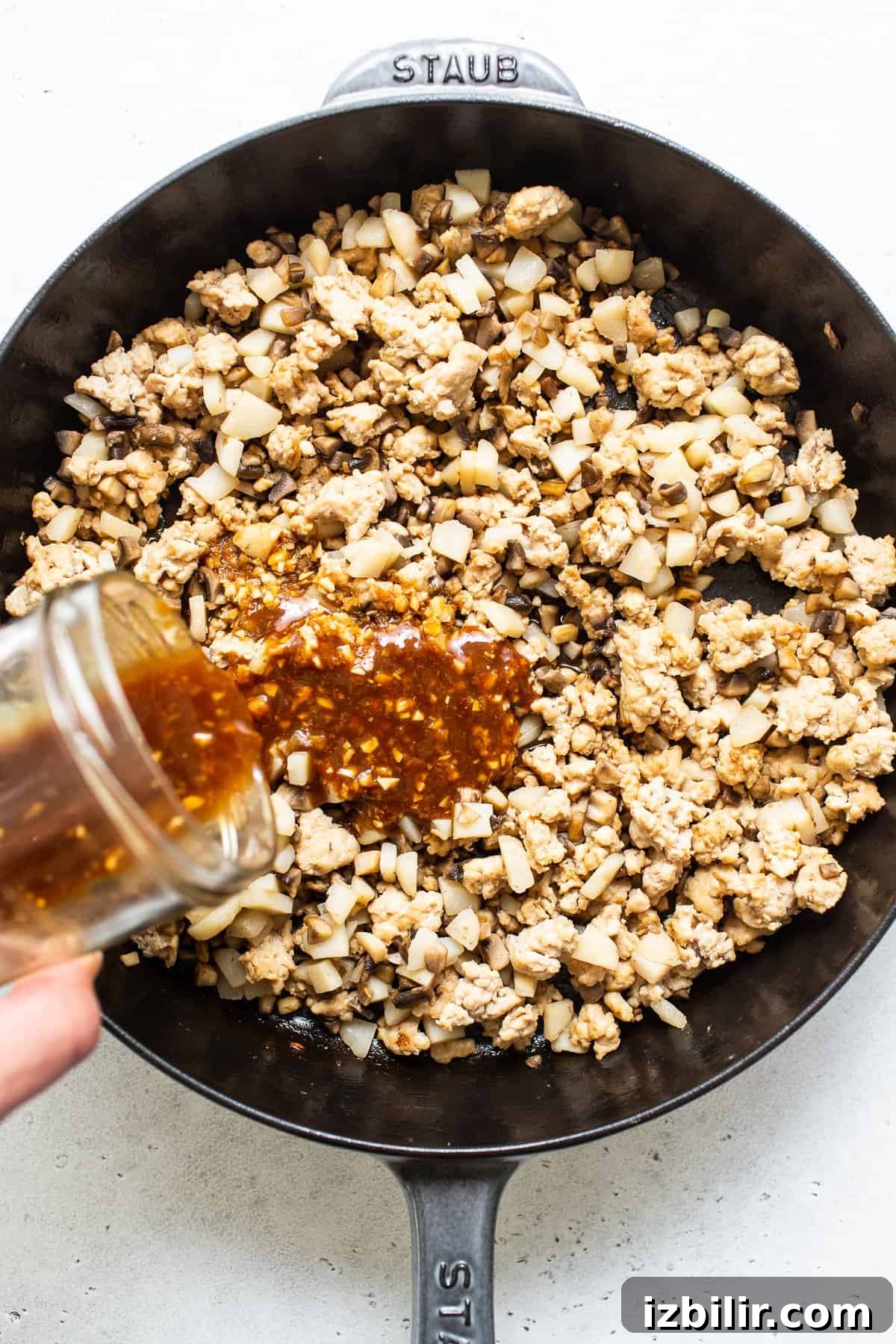 Pouring sauce onto ground chicken. pouring sauce onto ground chicken.